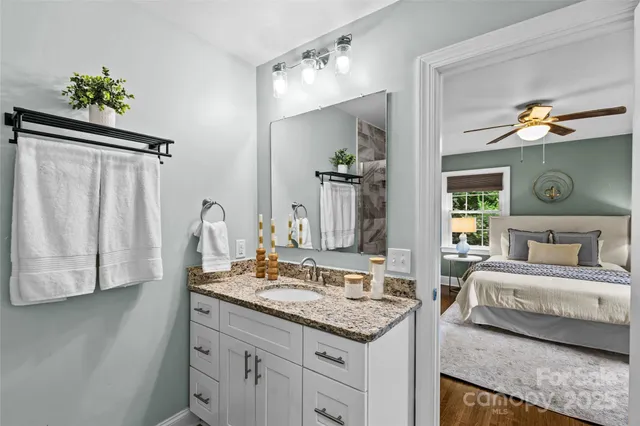 a en suite bathroom with a granite countertop sink and a mirror