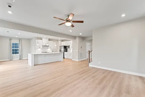a view of an empty room with kitchen and window