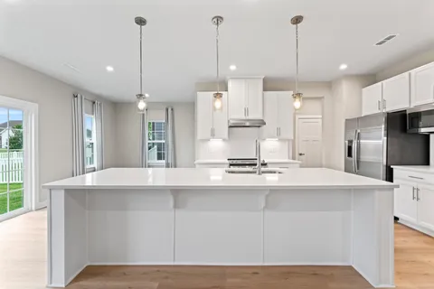 a kitchen with stainless steel appliances kitchen island granite countertop a sink a stove and a refrigerator