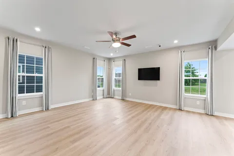 an empty room with wooden floor and a ceiling fan