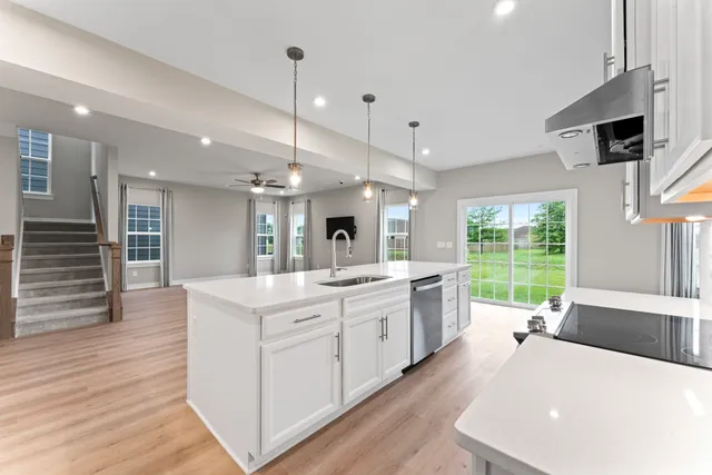 a large white kitchen with a large window a sink and stainless steel appliances