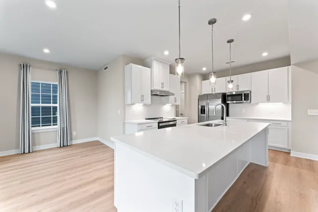 a large kitchen with kitchen island a stove a sink a center island and wooden floor