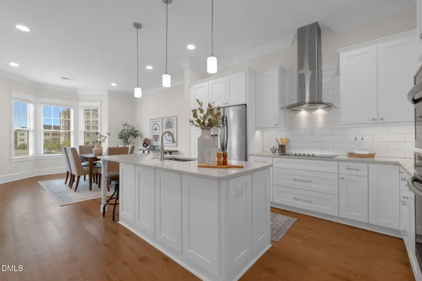 a kitchen with stainless steel appliances a refrigerator a stove a sink and white cabinets