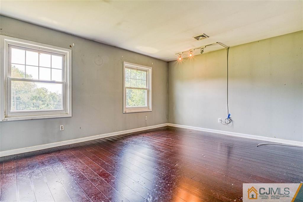 207 Fresh Ponds Road Monroe Township, NJ 08831 - Photo 22 of 25 an empty room with wooden floor and windows