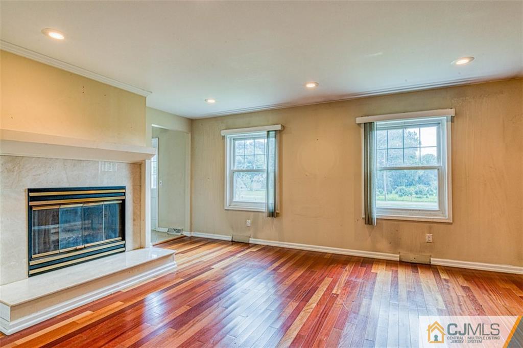 207 Fresh Ponds Road Monroe Township, NJ 08831 - Photo 8 of 25 a view of an empty room with wooden floor fireplace and a window