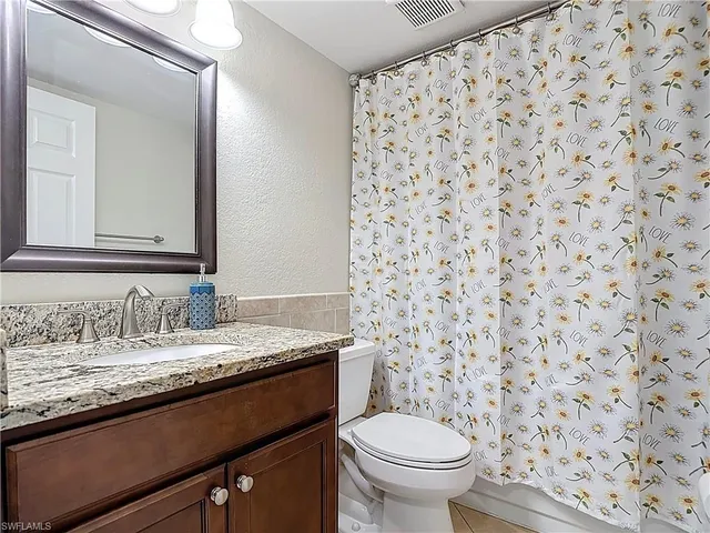 a bathroom with a granite countertop sink a toilet and a mirror