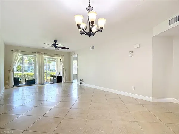 a view of an empty room with a chandelier fan and windows