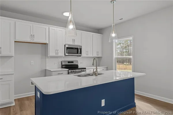 a kitchen with sink a microwave a stove and cabinets