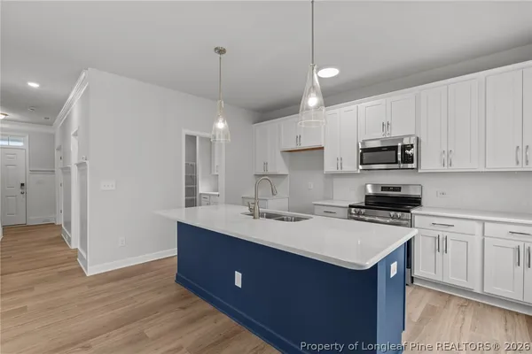 a kitchen with kitchen island a sink a stove a refrigerator and white cabinets