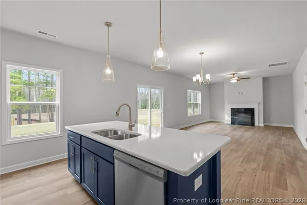 a kitchen with a sink chandelier and wooden floor