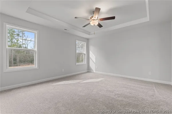 an empty room with chandelier fan and windows