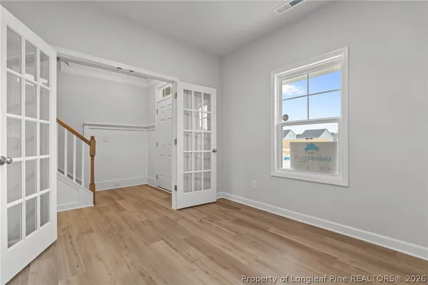 an empty room with wooden floor cabinet and windows