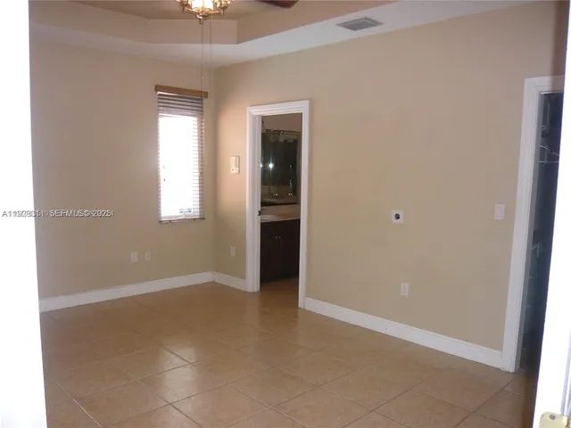 an empty room with chandelier fan and windows