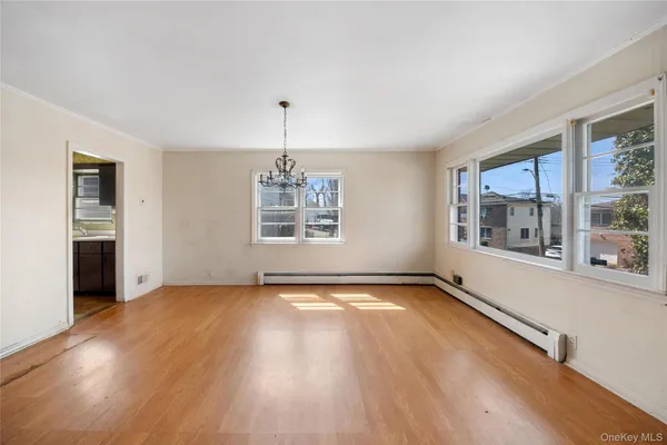 a view of an empty room with a window and wooden floor