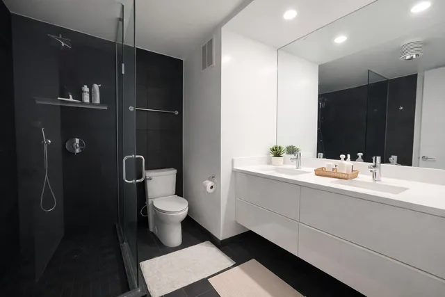 a bathroom with a double vanity sink toilet and a mirror
