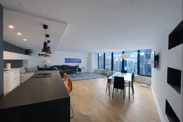 a living room with furniture a flat screen tv and kitchen view