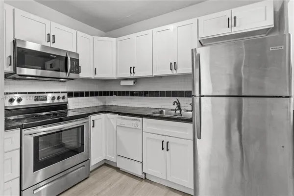 a kitchen with stainless steel appliances white cabinets white stove a microwave and a refrigerator