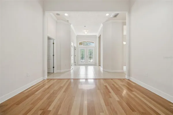 an empty room with chandelier fan and windows