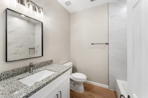 a bathroom with a granite countertop sink a toilet and a mirror