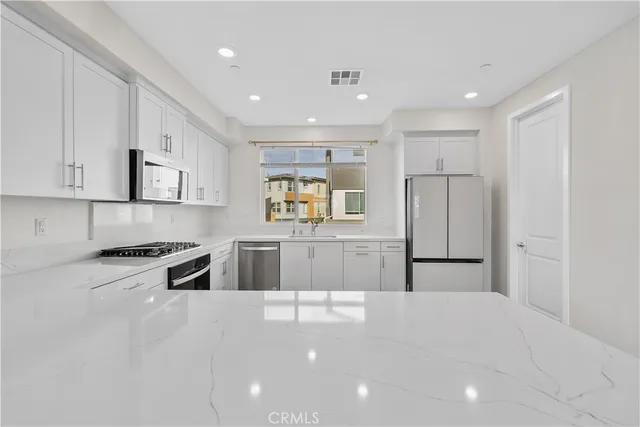 a large white kitchen with cabinets appliances and a counter space