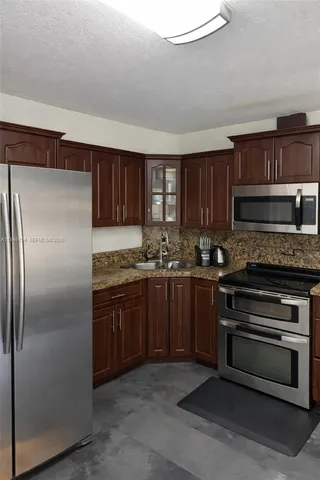 a kitchen with kitchen island granite countertop wooden cabinets stainless steel appliances and a window