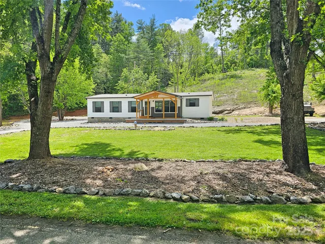 a front view of a house with a yard and a large tree