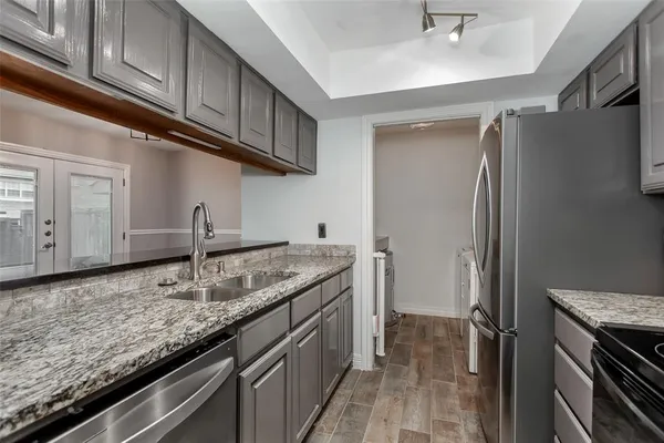 a kitchen with granite countertop stainless steel appliances a sink stove and cabinets