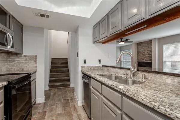 a kitchen with granite countertop a sink stainless steel appliances and cabinets