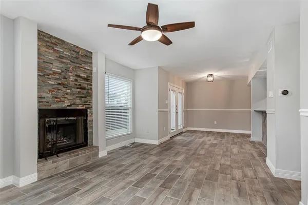a view of an empty room with wooden floor fireplace and a window