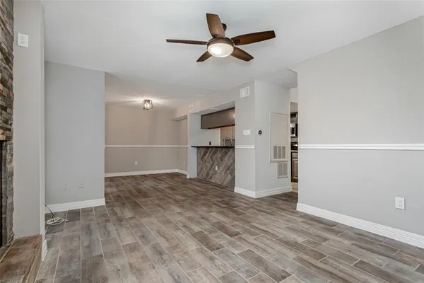 a view of empty room with wooden floor and ceiling fan