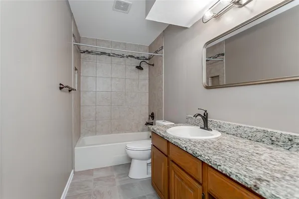 a bathroom with a granite countertop sink a toilet and shower
