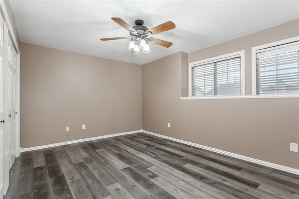 a view of an empty room with chandelier fan and a window