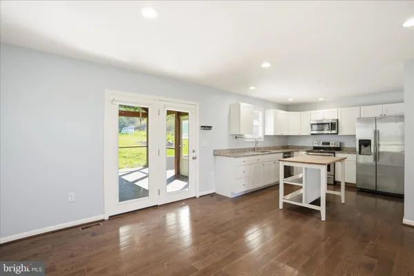 an empty room with wooden floor and kitchen view