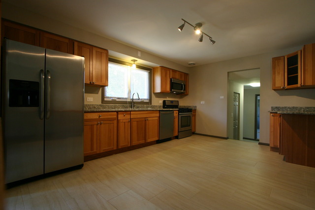 10549 Oak Park Avenue Chicago Ridge, IL 60415 - Photo 10 of 25 a kitchen with stainless steel appliances granite countertop a refrigerator a sink a stove a washer dryer and a dining table