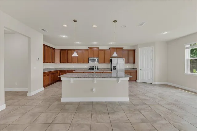 a large kitchen with stainless steel appliances kitchen island granite countertop a stove a sink a microwave and a refrigerator