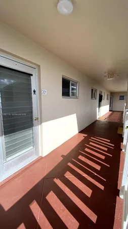 an empty room with wooden floor cabinet and windows