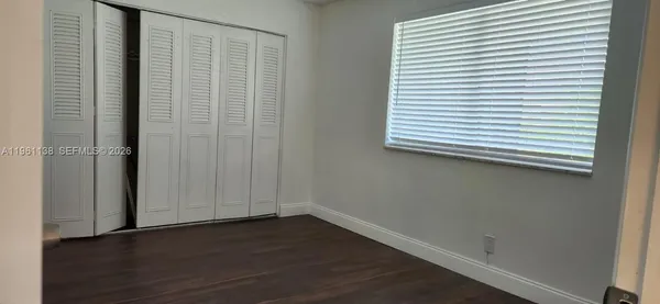 an empty room with wooden floor and a window with blinds