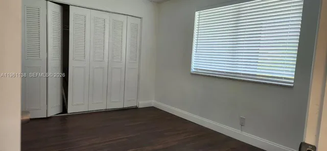 an empty room with wooden floor and a window with blinds
