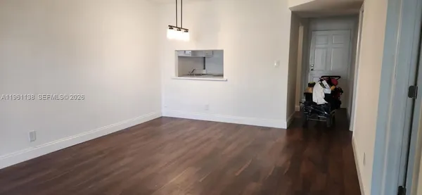 a view of a hallway with wooden floor and a bathroom