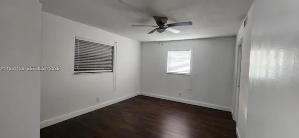a view of empty room with wooden floor and fan