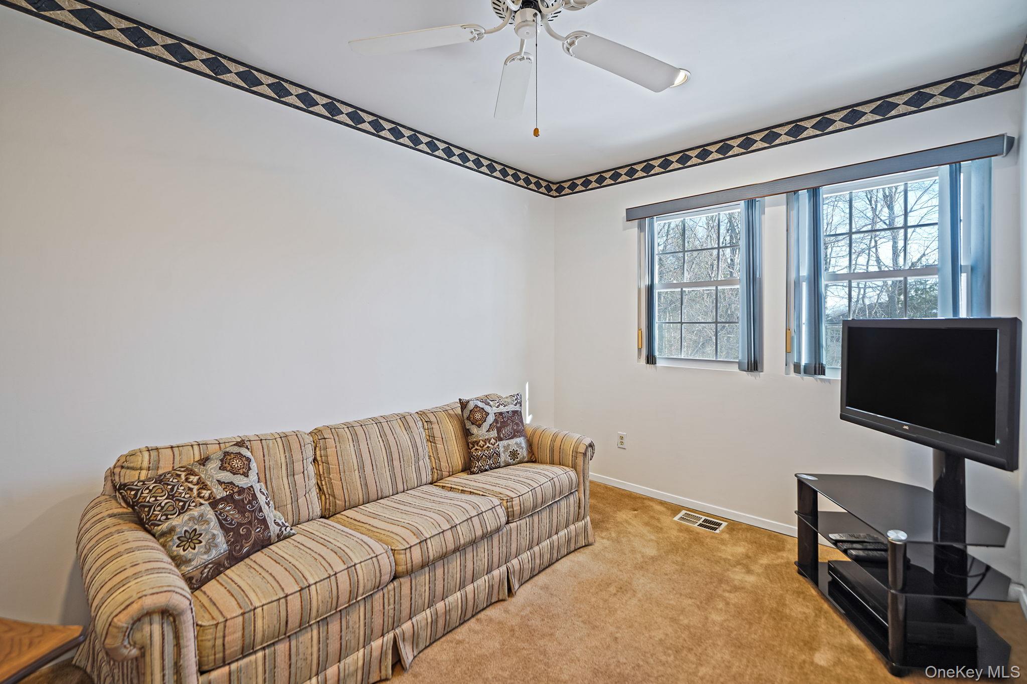 8 Huntington Commons, Unit 8 Yaphank, NY 11980 - Photo 13 of 30 a living room with furniture a flat screen tv and a window