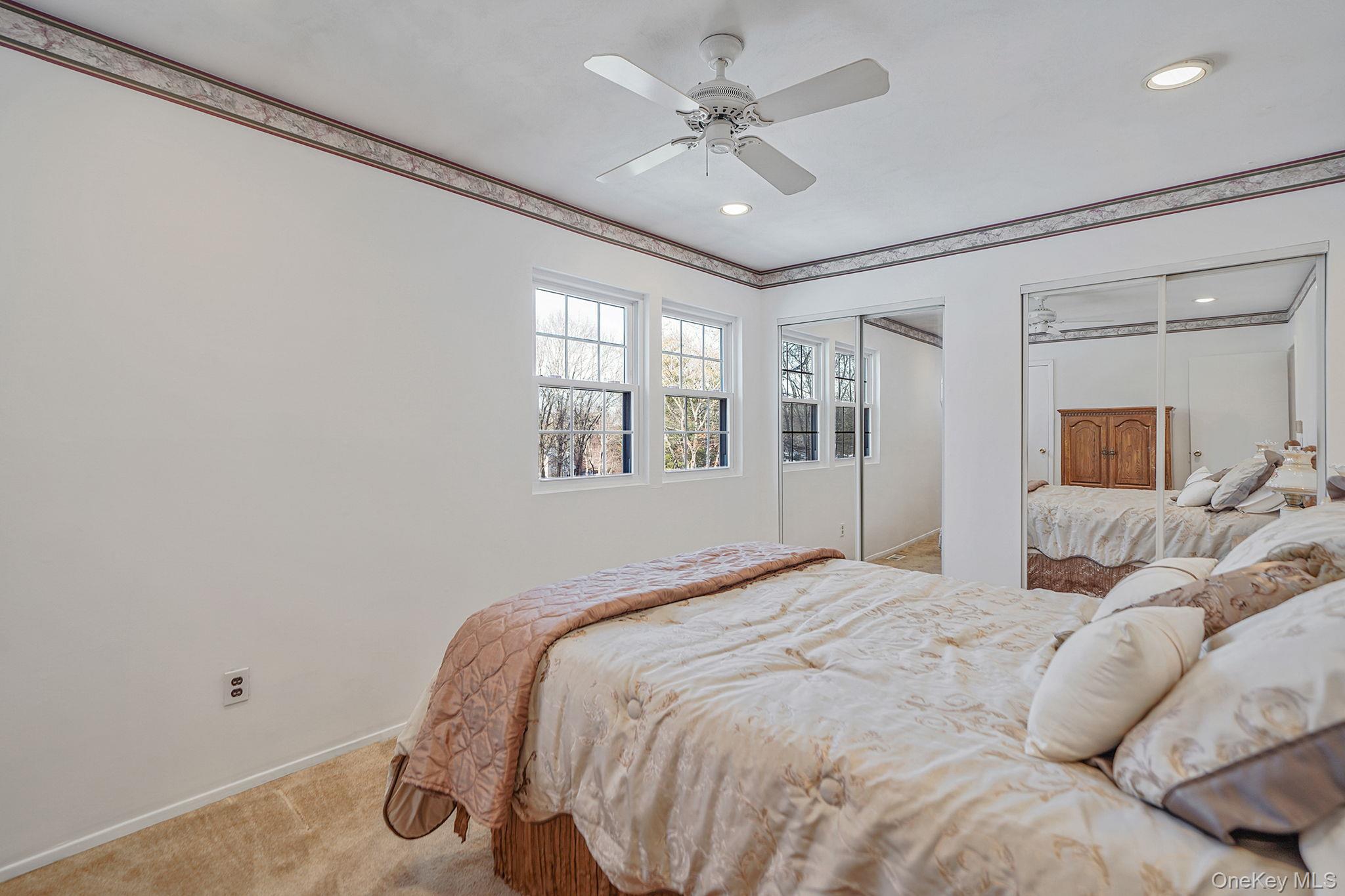 8 Huntington Commons, Unit 8 Yaphank, NY 11980 - Photo 20 of 30 a bedroom with a large bed and a chandelier