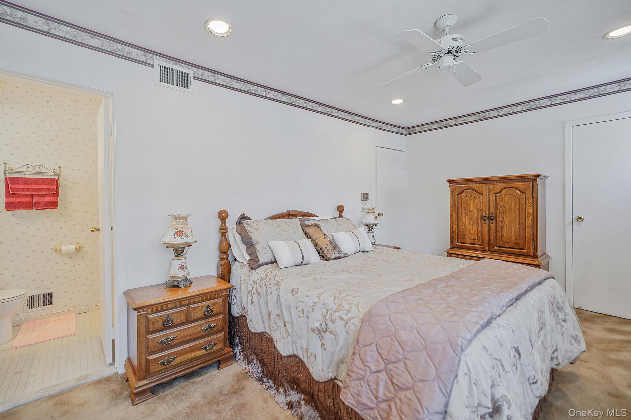 8 Huntington Commons, Unit 8 Yaphank, NY 11980 - Photo 22 of 30 a bedroom with a bed and a chandelier