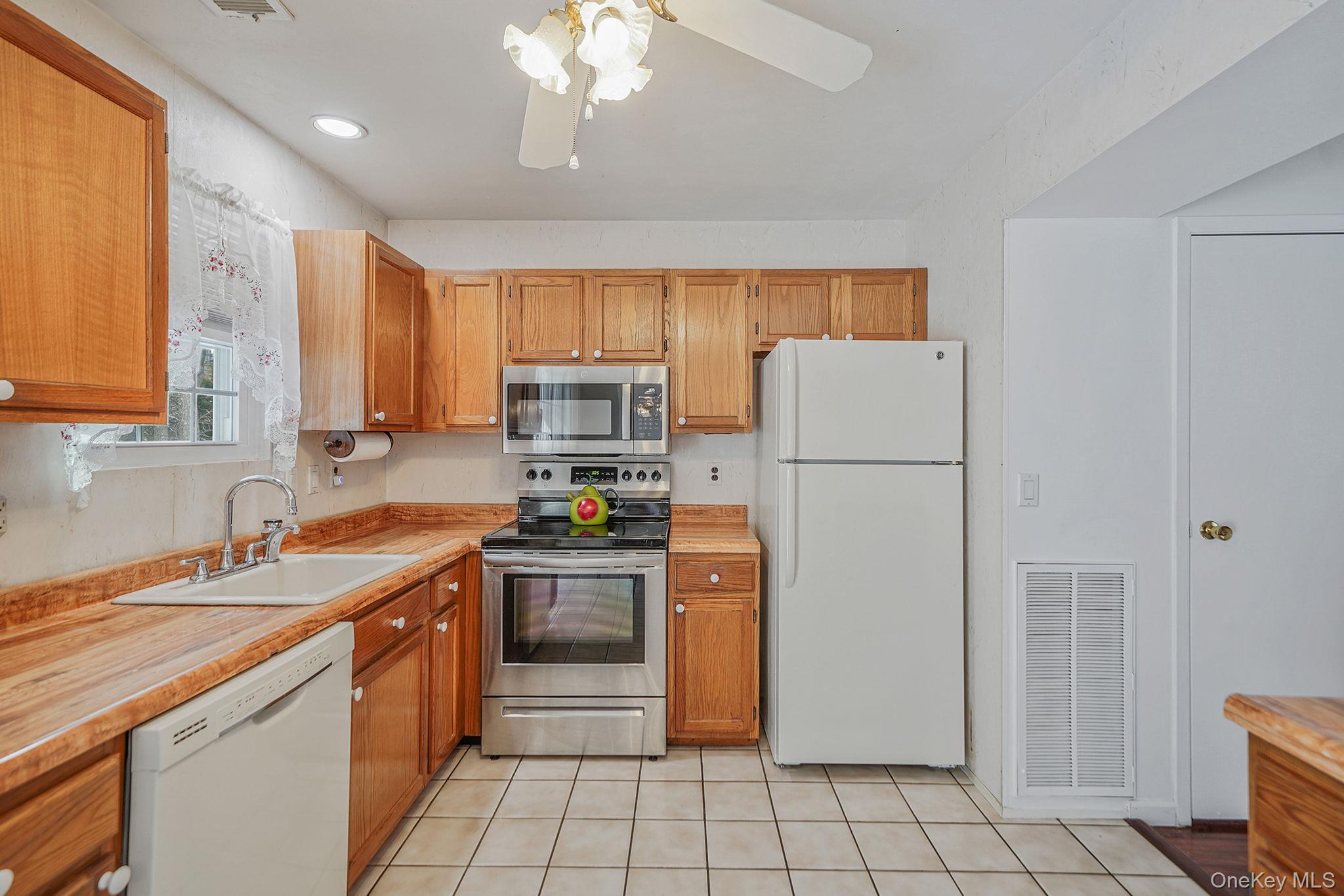 8 Huntington Commons, Unit 8 Yaphank, NY 11980 - Photo 9 of 30 a kitchen with stainless steel appliances granite countertop a refrigerator a sink dishwasher a stove with white cabinets