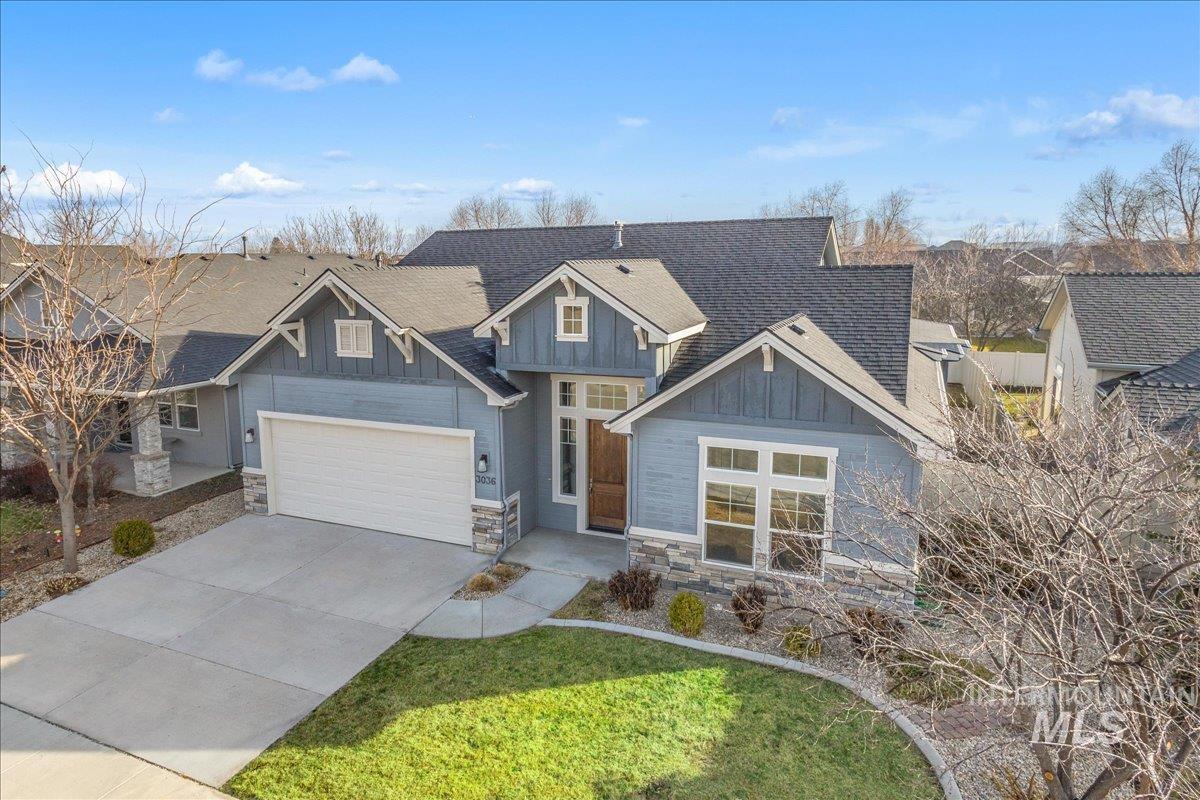 Craftsman-style house featuring stone siding, board and batten siding, driveway, and a shingled roof