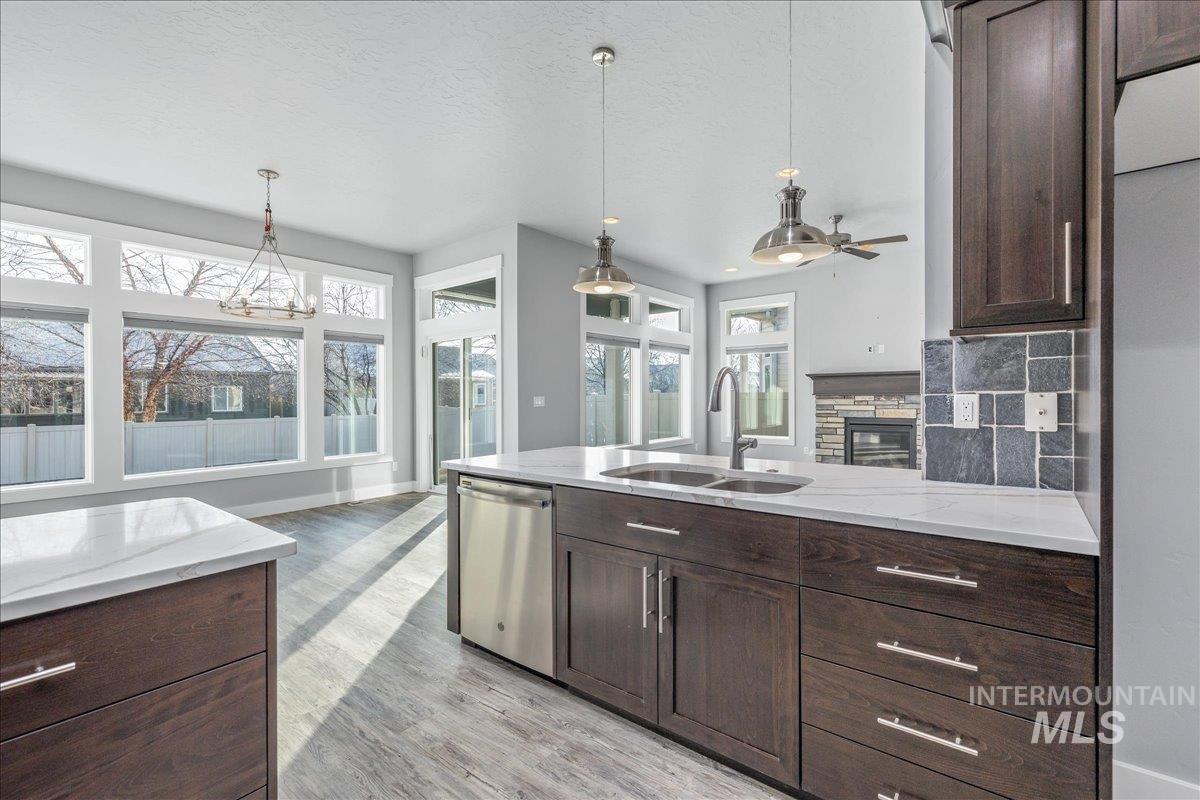 3036 Northwest 13th Street Meridian, ID 83646 - Photo 13 of 50 Kitchen with dark wood finish cabinets, backsplash, dishwasher, decorative light fixtures, and a textured ceiling