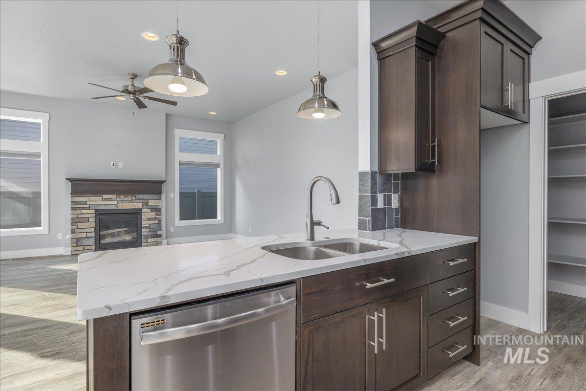 3036 Northwest 13th Street Meridian, ID 83646 - Photo 14 of 50 Kitchen featuring dark wood finish cabinetry, light stone counters, dishwasher, and pendant lighting