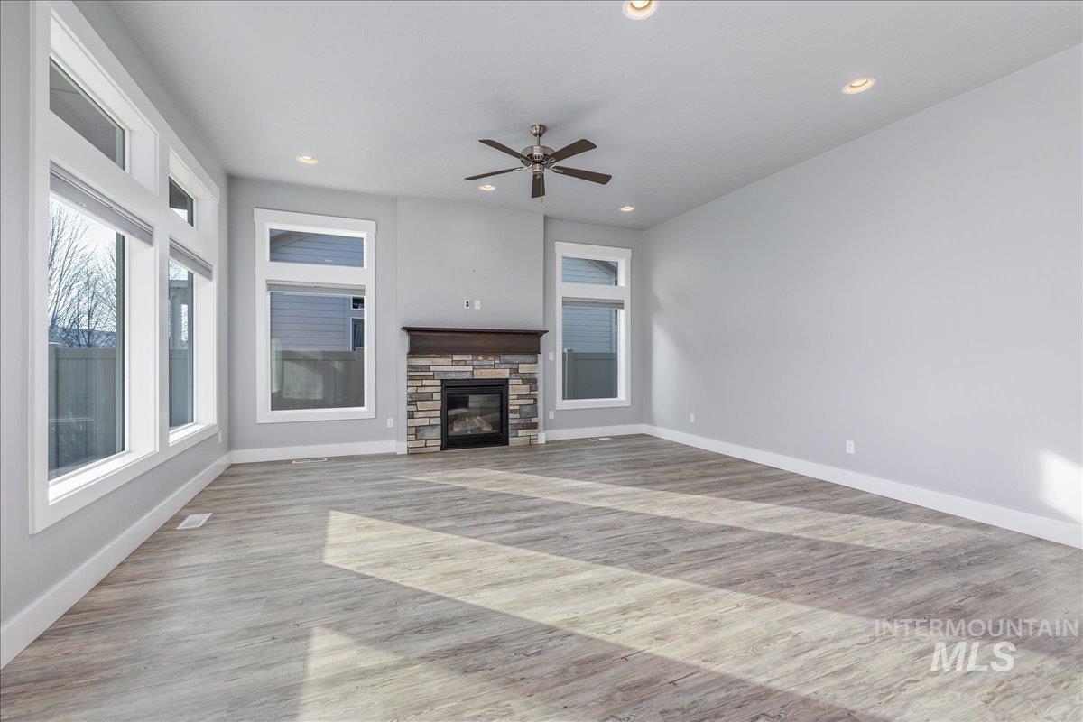 3036 Northwest 13th Street Meridian, ID 83646 - Photo 20 of 50 Unfurnished living room with a stone fireplace, recessed lighting, a ceiling fan, and light wood-style floors