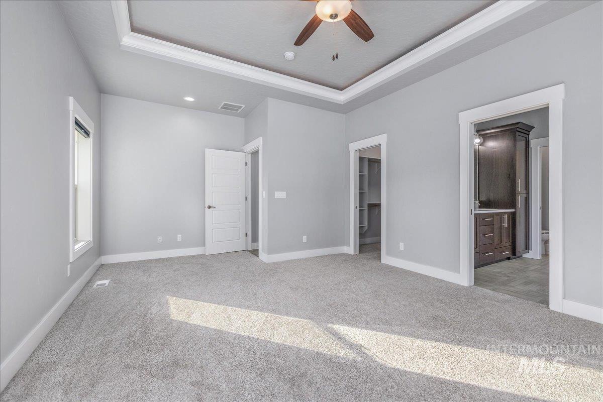 3036 Northwest 13th Street Meridian, ID 83646 - Photo 22 of 50 Unfurnished bedroom with a walk in closet, light carpet, ceiling fan, a tray ceiling, and ensuite bathroom