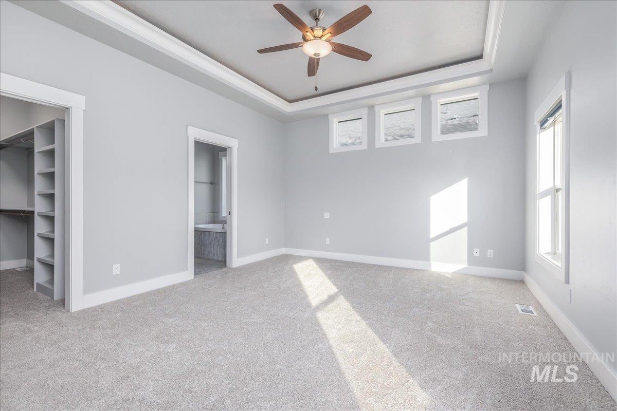 3036 Northwest 13th Street Meridian, ID 83646 - Photo 24 of 50 Unfurnished bedroom featuring a spacious closet, a raised ceiling, light colored carpet, ceiling fan, and connected bathroom
